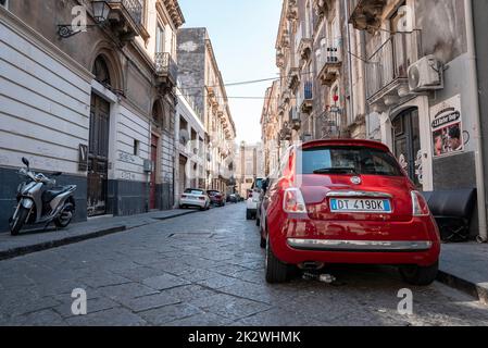 Auto e scooter parcheggiati sul lato della strada tra vecchi edifici in città Foto Stock