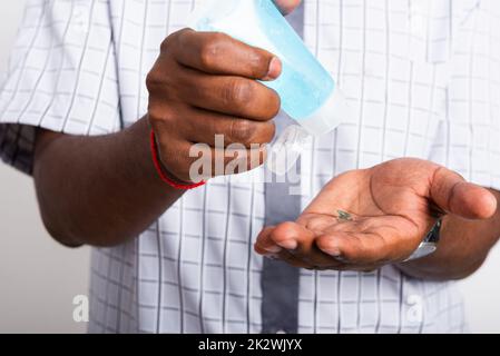 uomo nero indossare maschera protettiva utilizzare gel igienizzante viso pulire la mano Foto Stock
