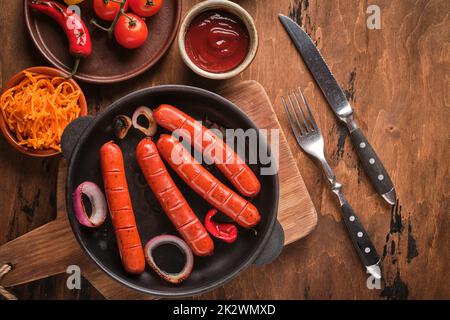 Salsicce grigliate in padella con cipolle e verdure Foto Stock