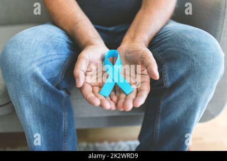 Uomo anziano che tiene un nastro blu di consapevolezza del cancro Foto Stock