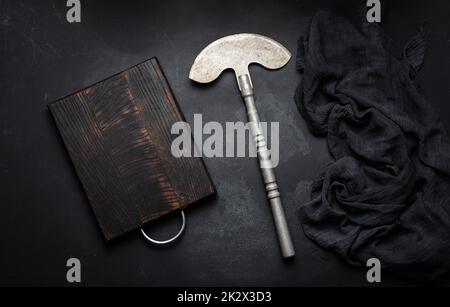 Tagliere in legno vuoto rettangolare e coltello da cucina su tavola nera con tovagliolo a garza, vista dall'alto Foto Stock