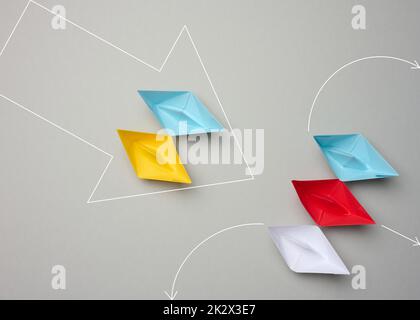 Due gruppi di barche di carta si trovano di fronte. Il giallo-blu costringe un gruppo di navi a ritirarsi. Foto Stock