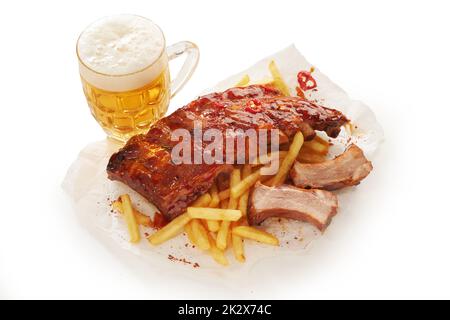 Tazza di birra e costolette di maiale sul tavolo Foto Stock