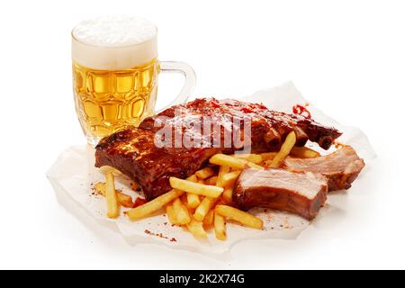 Birra fredda e costolette di maiale sul tavolo Foto Stock