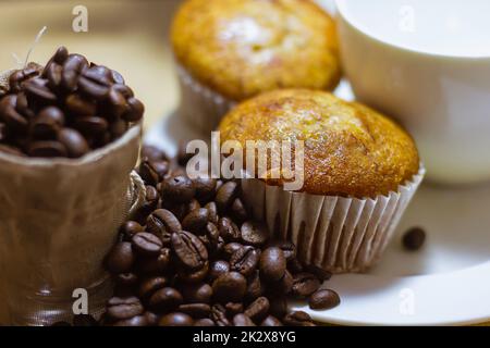 Banana cake messo in un piatto e caffè in grani sul lato Foto Stock
