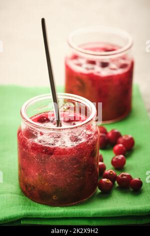 Marmellata di mirtilli rossi in un recipiente di vetro con frutti di bosco freschi da vicino. Foto Stock