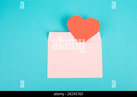 Busta rosa con un cuore rosso, spazio vuoto copia, sfondo blu, biglietto di auguri valintine giorno, posta romantica, lettera d'amore Foto Stock