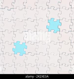 Puzzle bianco su sfondo blu, parti mancanti, lavorare insieme in squadra, cercare soluzioni, l'ultimo pezzo Foto Stock