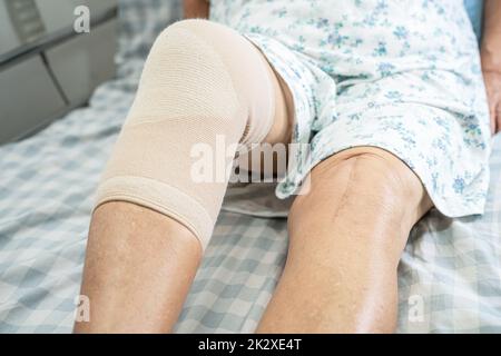 Donna anziana asiatica anziana o anziana paziente con supporto ginocchio dolore articolare a letto in reparto ospedale infermieristico, sano forte concetto medico. Foto Stock