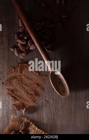 Vista dall'alto di cacao in polvere e fagioli con un cucchiaio sul tavolo Foto Stock