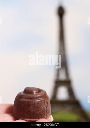 Tartufi francesi al cioccolato in mano con la sfocata Torre Eiffel sullo sfondo Foto Stock