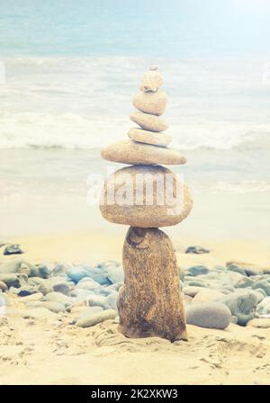 Pietre equilibrato su una spiaggia di ciottoli durante il tramonto. Foto Stock