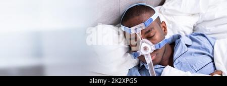 Uomo che indossa la maschera CPAP che dorme sul letto Foto Stock