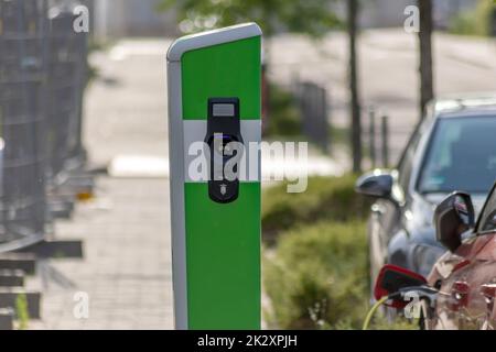 La ricarica delle auto elettriche presso la stazione di ricarica pubblica con energia rinnovabile per i veicoli elettrici e le emissioni di CO2 ecocompatibili e l'energia verde seguono lo schema governativo per le auto alimentate a batteria Foto Stock