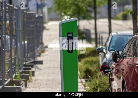 La ricarica delle auto elettriche presso la stazione di ricarica pubblica con energia rinnovabile per i veicoli elettrici e le emissioni di CO2 ecocompatibili e l'energia verde seguono lo schema governativo per le auto alimentate a batteria Foto Stock