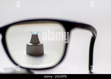 La lente a contatto blu attraverso gli occhiali neri mostra occhiali diversi per correggere la lungimiranza e la prossimità tramite optometria o medico oculare contro la miopia con correzione visiva degli occhi per una visione perfetta Foto Stock