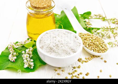 Infarinare il verde grano saraceno in una ciotola con olio su un asse di legno Foto Stock