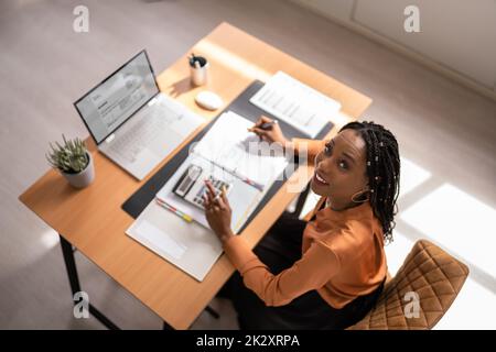 Donna d'affari che calcola l'imposta alla scrivania Foto Stock