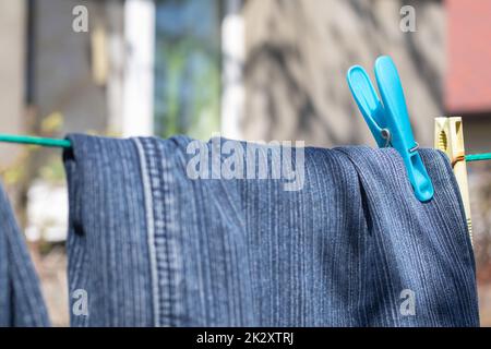 I jeans sono appesi su un vestito in una giornata di sole estate. Vista sui jeans appena lavati. Foto Stock