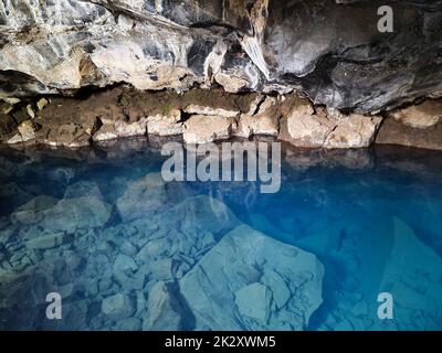 Ammira la grotta lavica di Grjotagja con acqua blu cristallina. Foto Stock