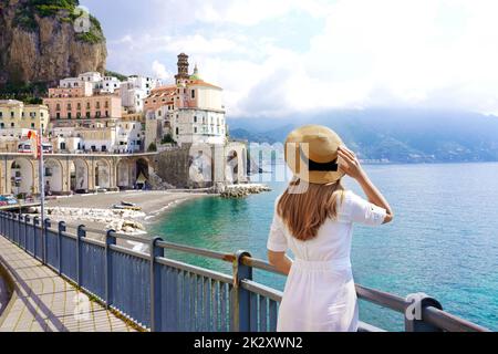 Turismo in Costiera Amalfitana. Vista posteriore della bella ragazza di moda godendo la vista del villaggio di Atrani sulla Costiera Amalfitana, Italia. Vacanze estive in Europa. Foto Stock