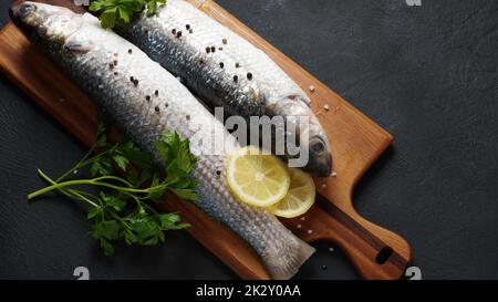 Pesce fresco triglie con lime, erbe e spezie su sfondo scuro. Foto Stock