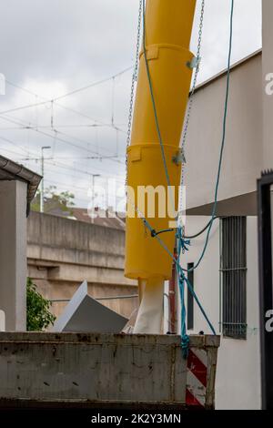 Scivolo di macerie gialle o scivolo di macerie sulla facciata della vecchia casa bianca aiuta con il rinnovamento e la ristrutturazione di vecchie proprietà per la rimozione di macerie pulite e la rimozione dei rifiuti in contenitore per cantiere Foto Stock