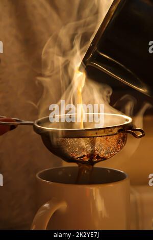 Giovane donna che usa il bollitore per preparare il tè in cucina Foto Stock