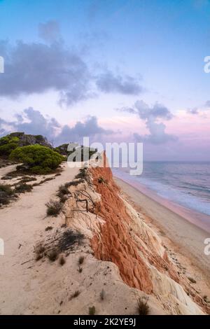 Tramonto colorato sullo splendido paesaggio di Praia de Falesia, regione dell'Algarve, Portogallo. Splendidi colori del cielo riflessi nell'acqua dell'oceano Foto Stock
