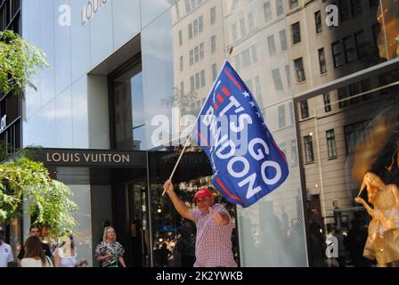 New York City, New York, USA - Settembre 10 2022: Un uomo che indossa un cappello rosso 'Make America Great Again' porta una bandiera 'Let's Go Brandon' su 5th Avenue. Foto Stock