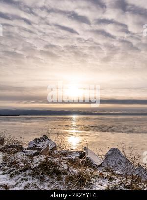 Una costa rocciosa innevata che si affaccia durante il tramonto a Tawas Bay, Michigan, USA Foto Stock