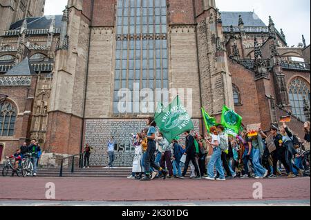 I manifestanti sono visti passare davanti ad una chiesa mentre tengono bandiere e cartelloni durante la manifestazione. Studenti e giovani provenienti da tutte le parti del paese si sono riuniti nella città olandese di Arnhem per chiedere un intervento sulle richieste delle comunità indigene, nere e di altre comunità emarginate per riappropriarsi delle loro terre. La giovane organizzazione climatica #FridaysForFuture ha organizzato questo marzo per continuare a chiedere una migliore politica climatica e per fermare la distruzione delle terre di MAPA (popolazioni e aree più colpite). Foto Stock