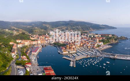 Veduta aerea della bellissima storica cittadina di pescatori di Bermeo, al tramonto. Barche ormeggiate nel porto. Vista panoramica della città. Foto Stock