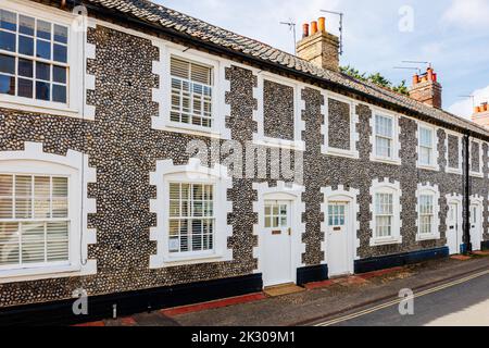 Terrazza di case di stile architettonico locale con pareti in pietra selce a Holt, una piccola città storica mercato georgiano nel nord Norfolk, Inghilterra Foto Stock