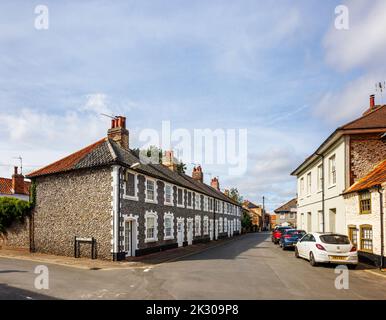 Terrazza di case di stile architettonico locale con pareti in pietra selce a Holt, una piccola città storica mercato georgiano nel nord Norfolk, Inghilterra Foto Stock