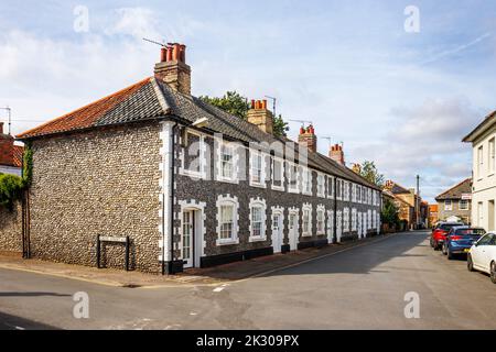 Terrazza di case di stile architettonico locale con pareti in pietra selce a Holt, una piccola città storica mercato georgiano nel nord Norfolk, Inghilterra Foto Stock