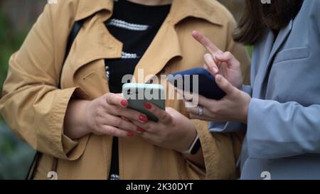 Le mani delle donne tengono gli smartphone. Le donne comunicano e utilizzano i telefoni. Foto Stock