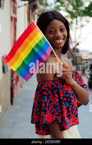 Felice giovane donna che tiene bandiera arcobaleno Foto Stock