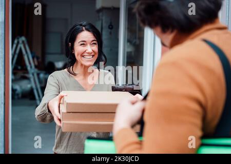 Donna felice che riceve il pacco da un addetto alla consegna Foto Stock