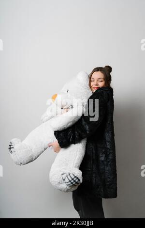Giovane donna sorridente che abbraccia orsetto in studio Foto Stock