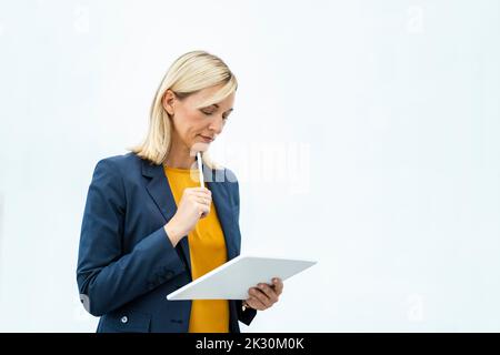 Donna d'affari pensata che utilizza un tablet PC su sfondo bianco Foto Stock