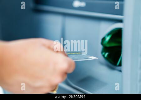 Mano di donna che inserisce la carta di credito nel bancomat Foto Stock