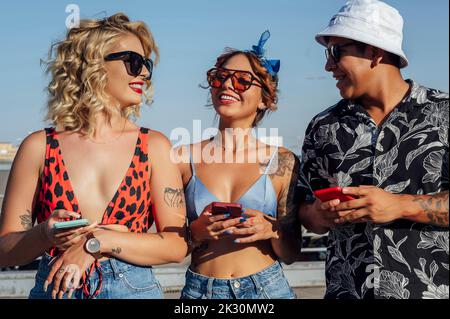 Uomo e donna con telefoni cellulari in piedi insieme nelle giornate di sole Foto Stock