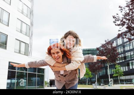 Allegra madre che dà cavalcata piggyback a figlia a Hafenity Foto Stock