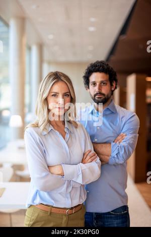 Professori fiduciosi con armi incrociate in biblioteca Foto Stock