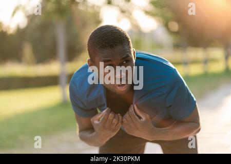 Giovane uomo stanco al parco nelle giornate di sole Foto Stock