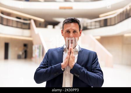 Un uomo d'affari maturo che saluta con le mani attaccate nella lobby Foto Stock