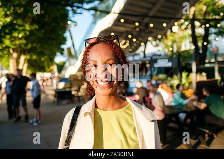 Felice giovane donna che indossa occhiali da sole godendo di una giornata di sole Foto Stock