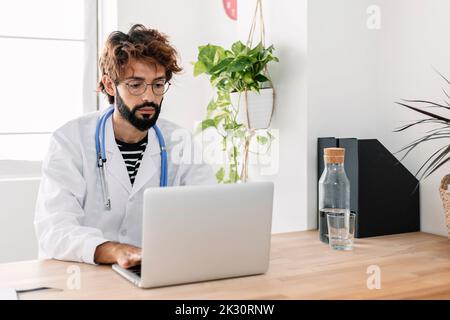 Medico che utilizza un computer portatile che lavora da casa Foto Stock