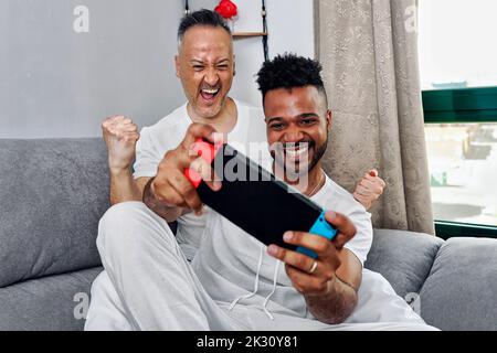 Felice uomo maturo che allietano il ragazzo giocando il video gioco Foto Stock